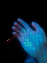 Close-up of hands shaking over a digital blueprint with neon highlights.