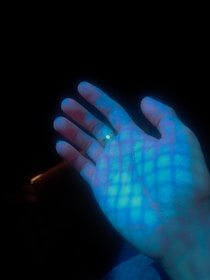 Close-up of hands shaking over a digital blueprint with neon highlights.