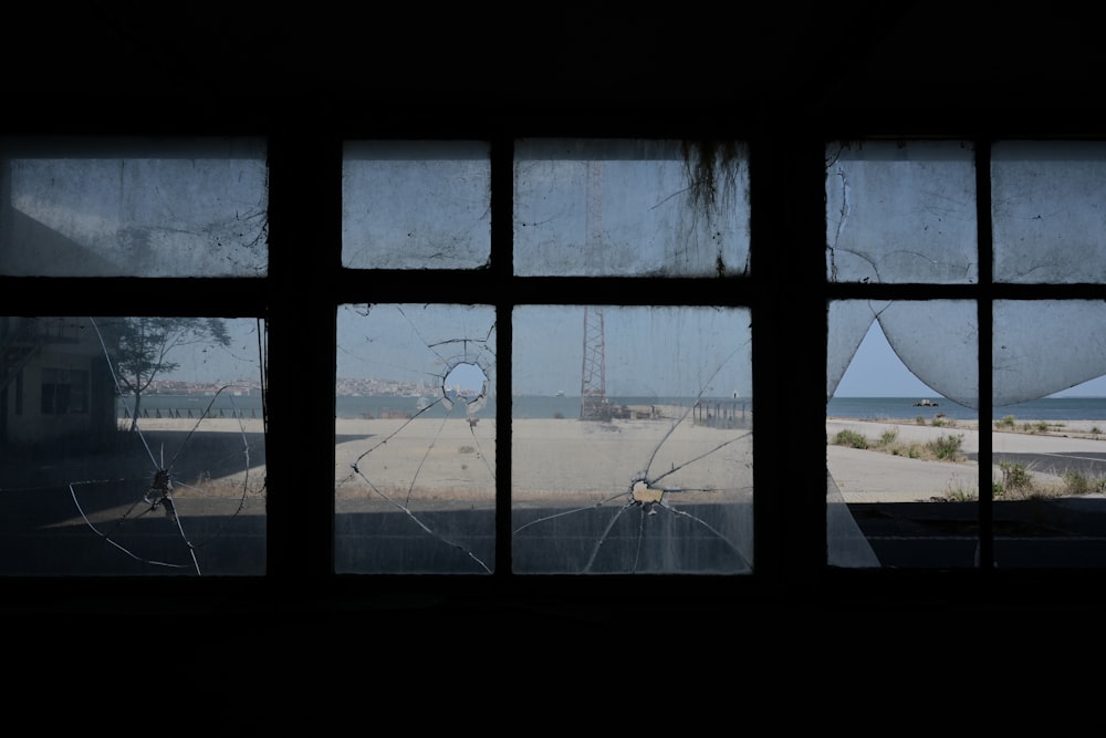 a broken window with a view of a beach