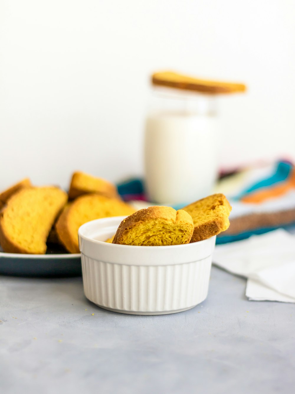 a white bowl filled with cookies next to a glass of milk