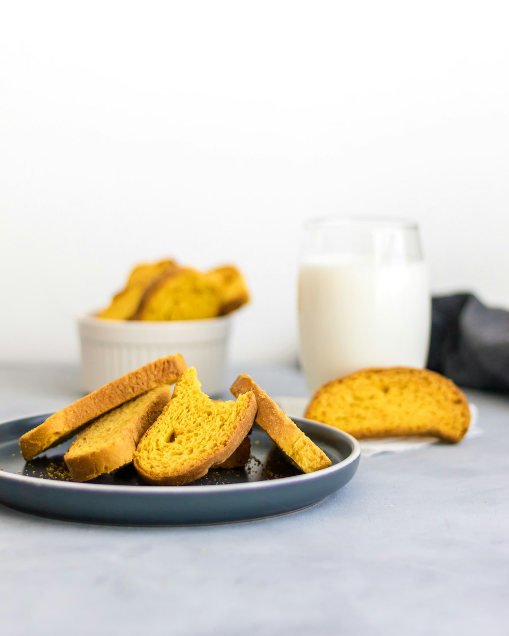 a plate of bread sticks next to a glass of milk