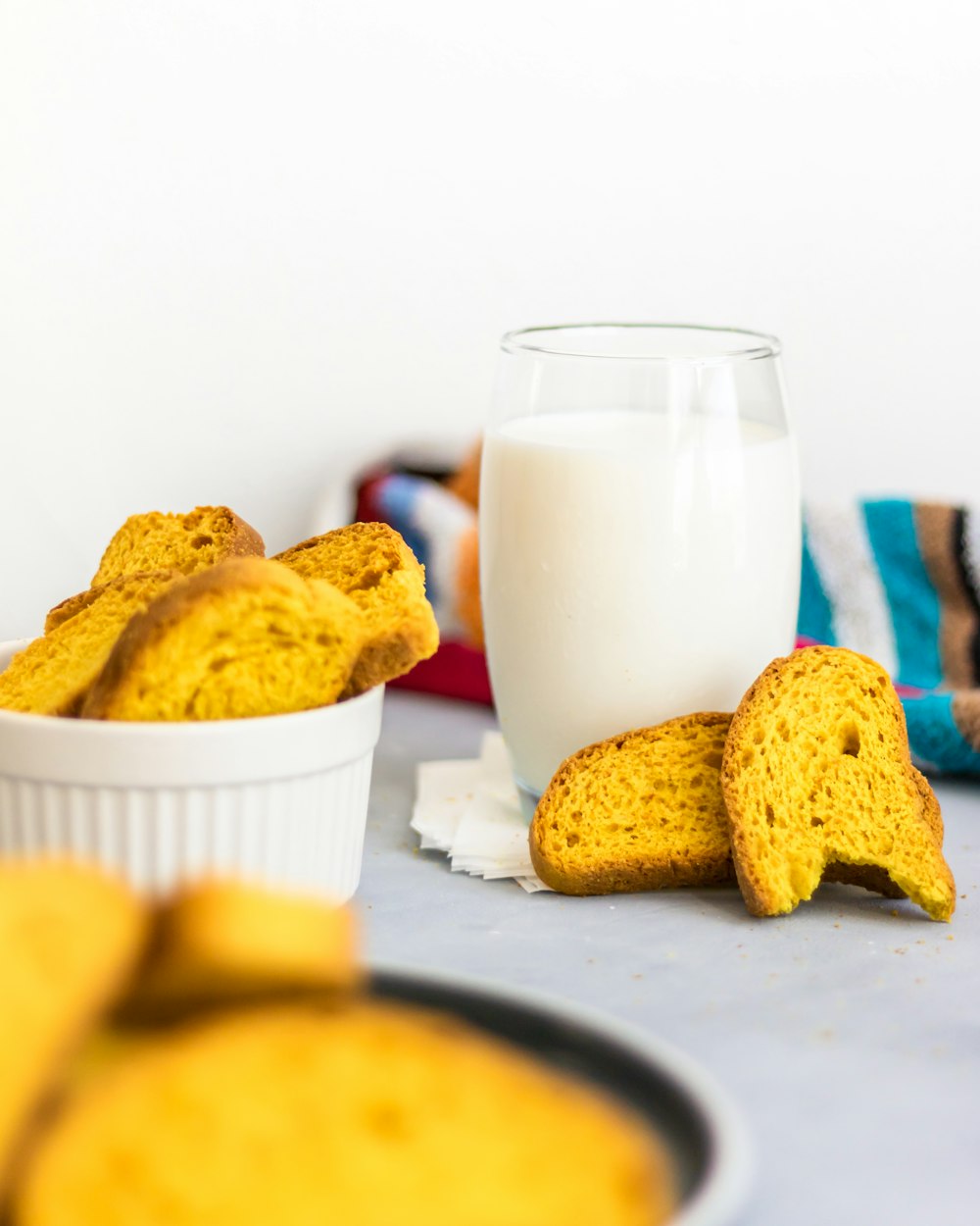 a glass of milk next to a bowl of cookies