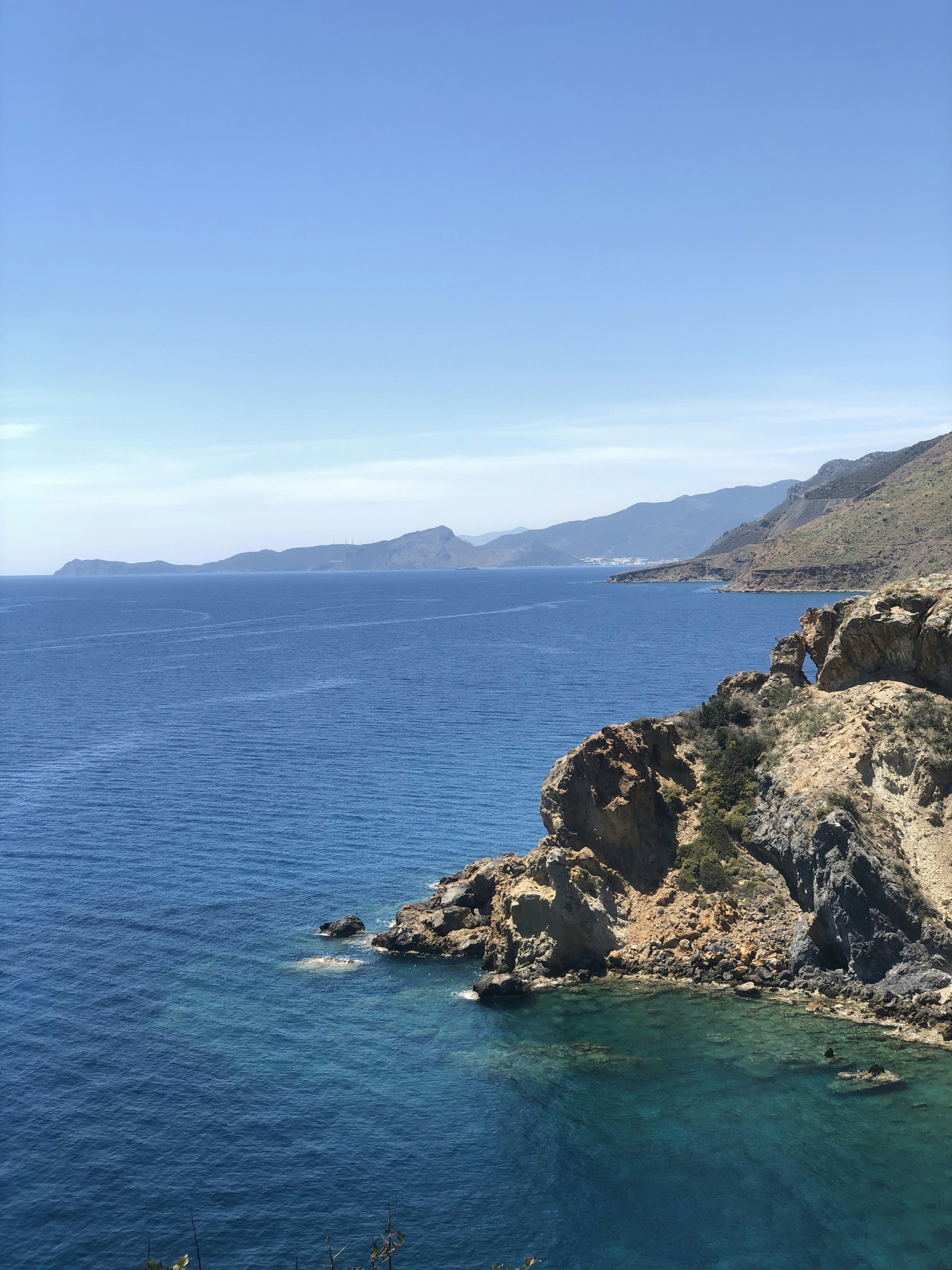 Crystal clear turquoise Mediterranean water with rocky coastline, bright sunlight, clean blue sky, pristine natural setting