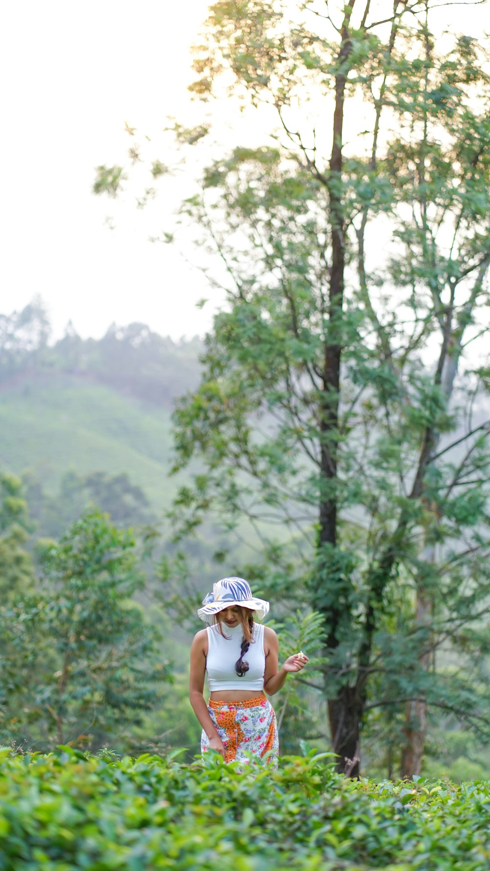 a woman standing in a field with a hat on