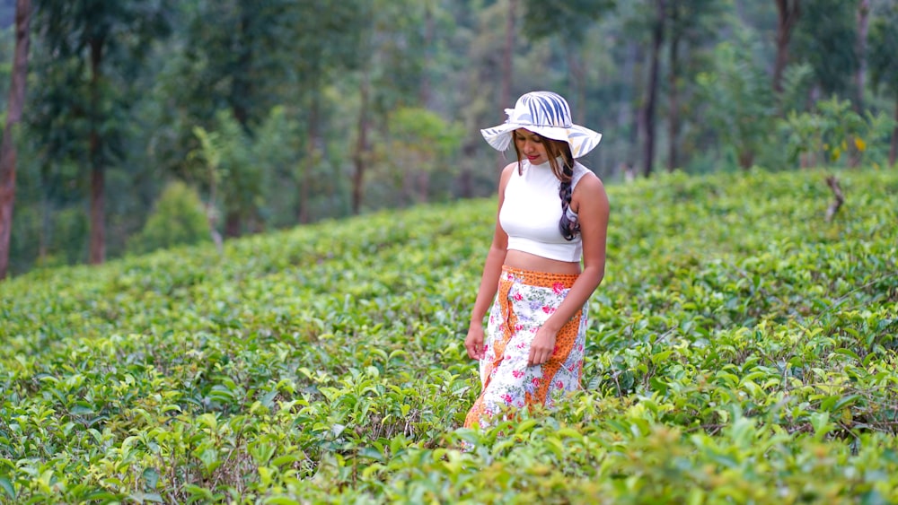 a woman standing in a field of tea bushes