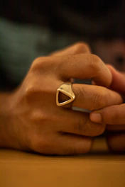 Close-up of a hand wearing minimalist geometric silver rings against a soft neutral background.