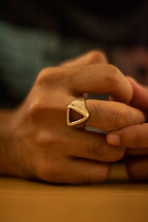 Close-up of a handcrafted wedding ring resting on a rustic wooden surface with soft natural light.