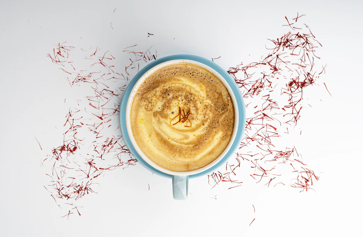 A flat white seen from above, with threads of saffron scattered around the cup