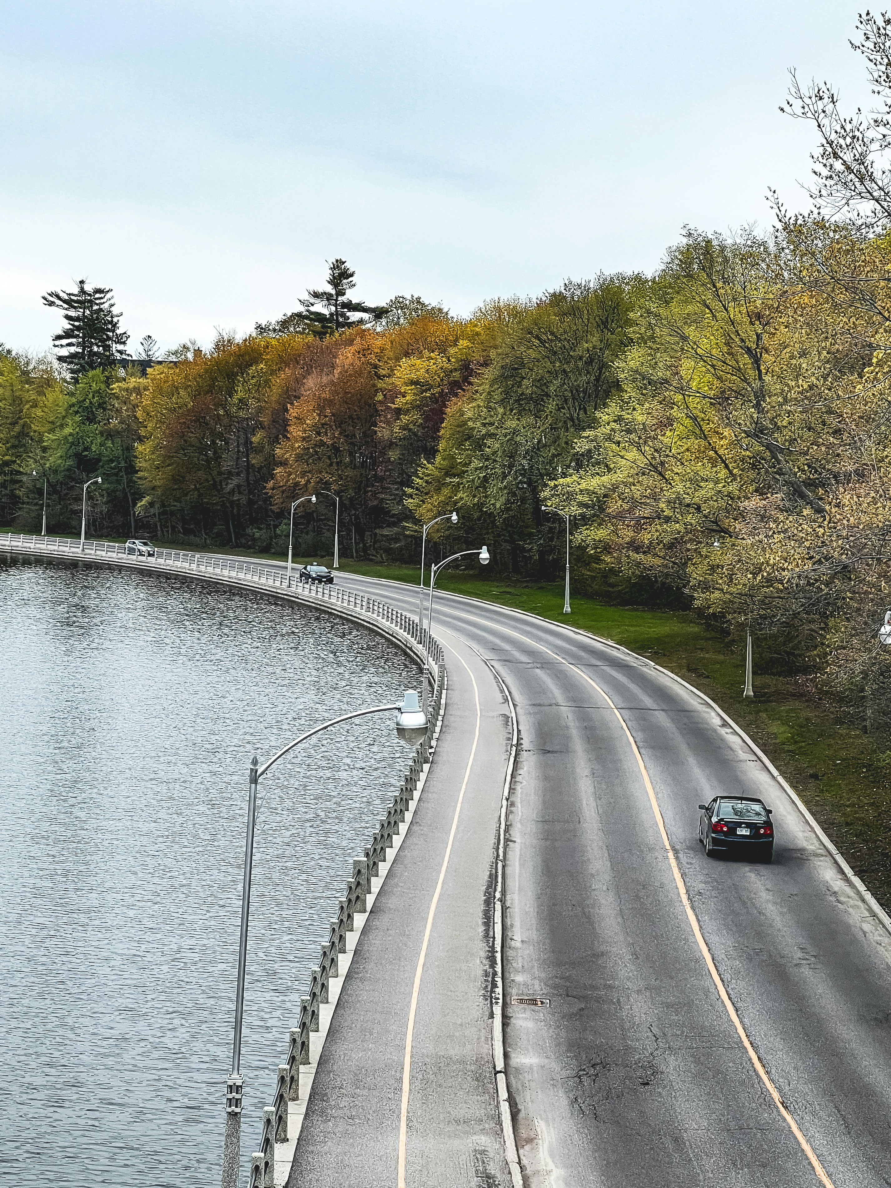 a car driving down a road next to a body of water