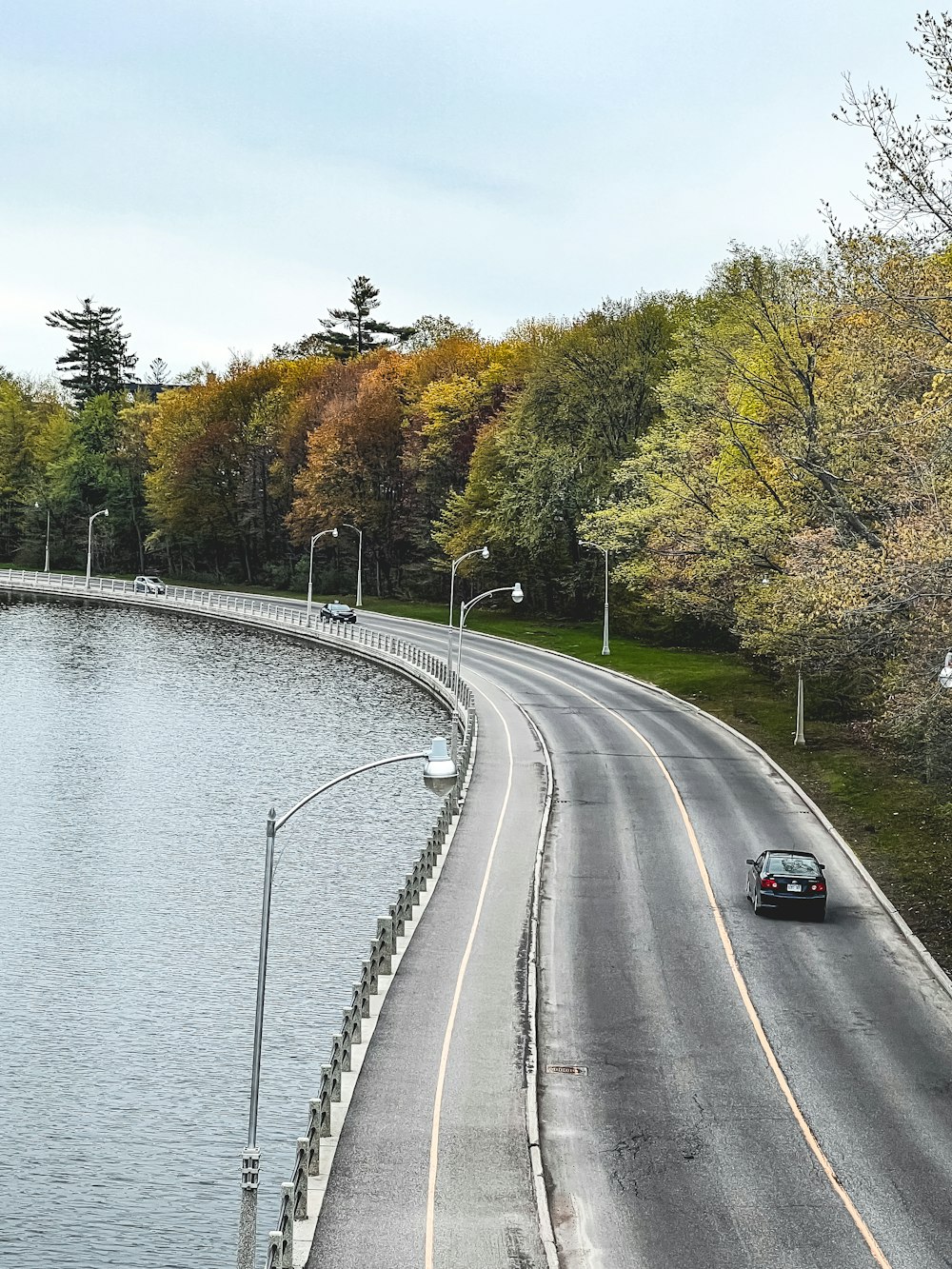 a car driving down a road next to a body of water