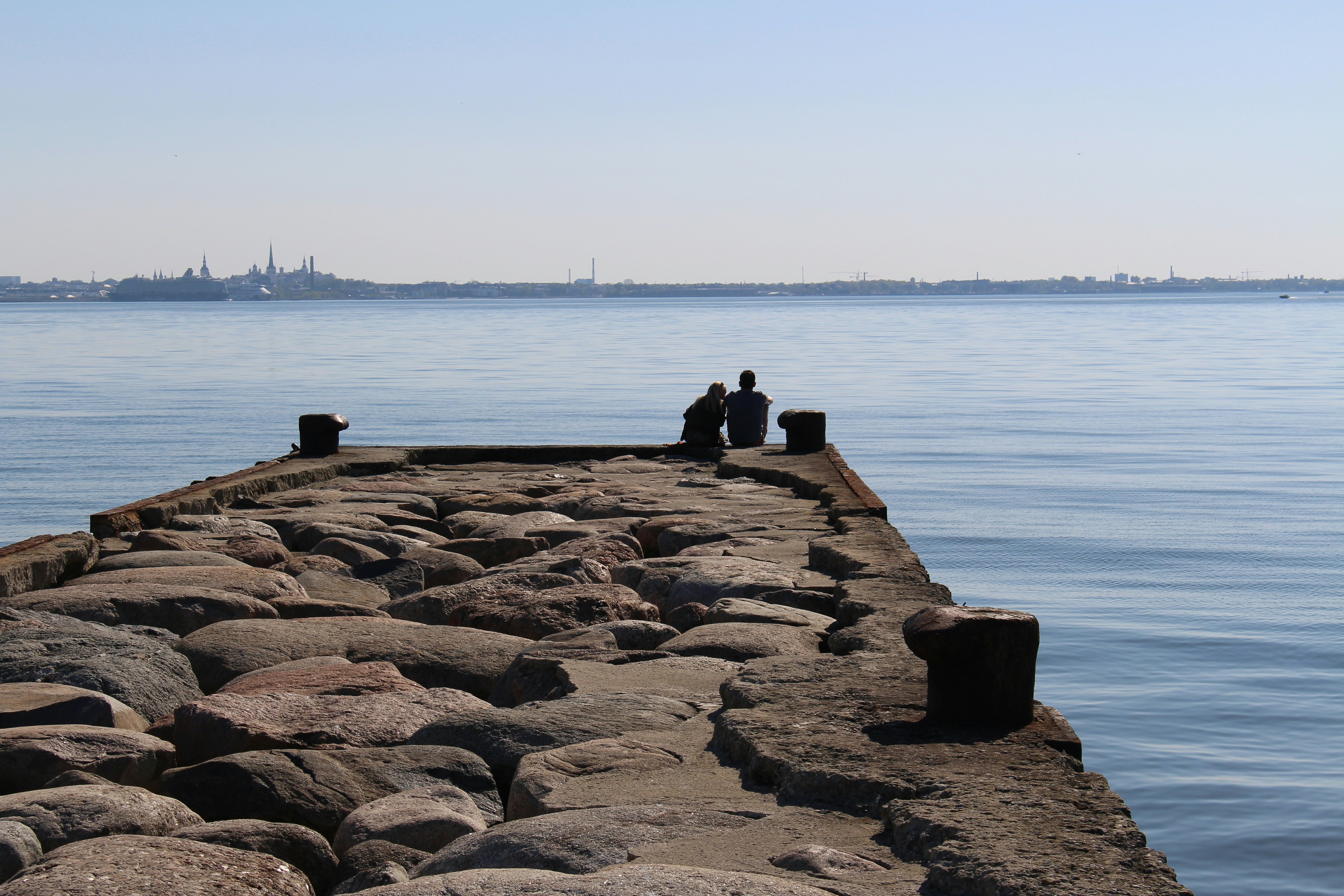a couple of people sitting on top of a stone pier