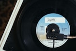 A close-up view of a vintage vinyl record on a turntable, with a focus on the label in the center, which reads 'Jugoton'. The record is spinning, and the needle is placed on it, hinting at the music being played.