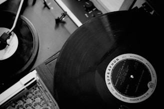Two vinyl records are placed on turntables, with one focused prominently, showing the label and grooves of the record in detail. The setup suggests a classic, retro audio system.