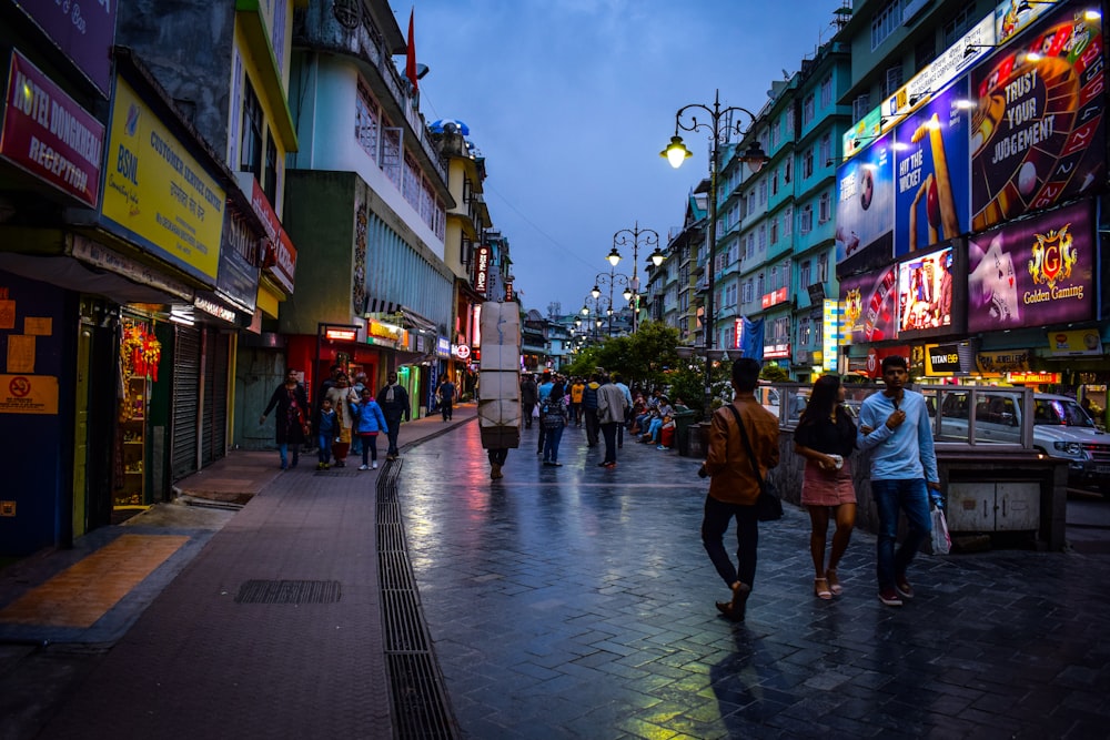 a group of people walking down a street next to tall buildings