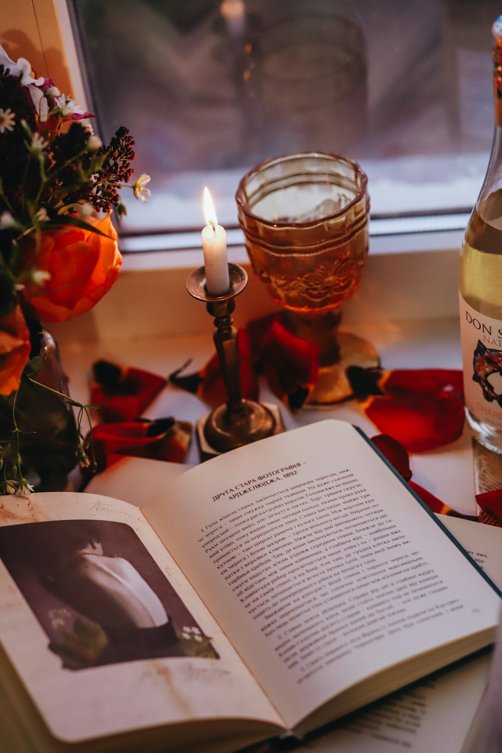 an open book sitting on top of a table next to a candle