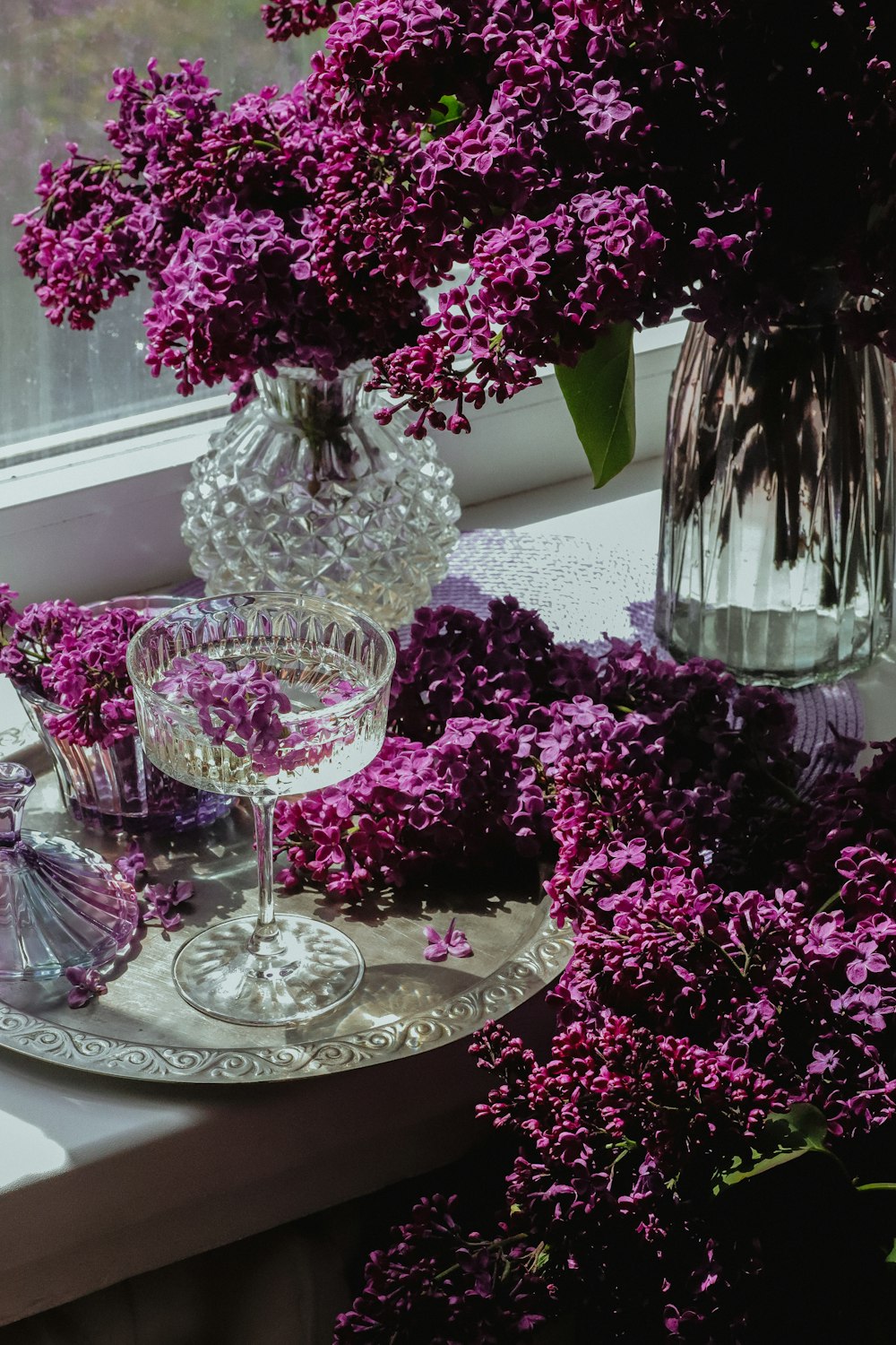 a glass of wine and some purple flowers on a table