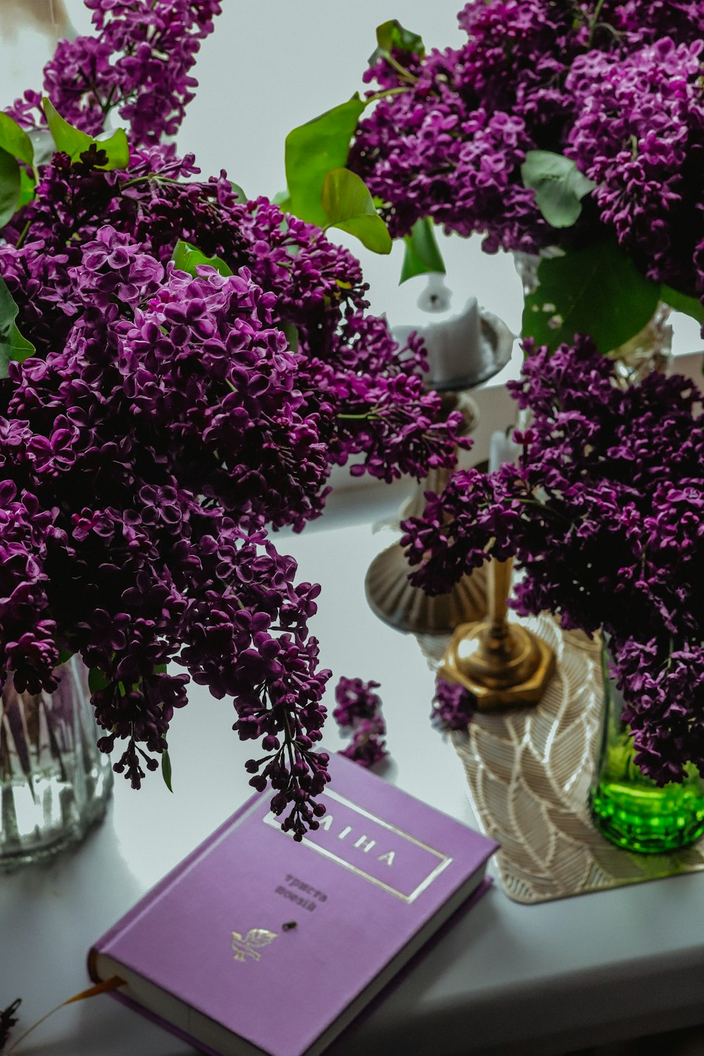 purple flowers in a vase and a book on a table