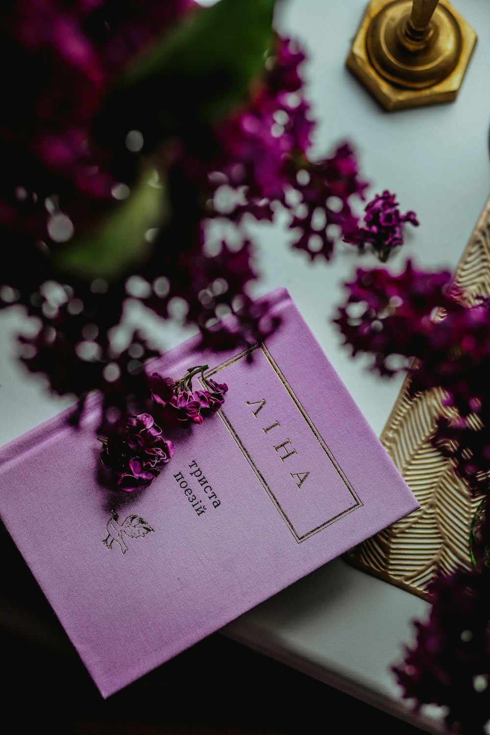 a purple book sitting on top of a table next to purple flowers