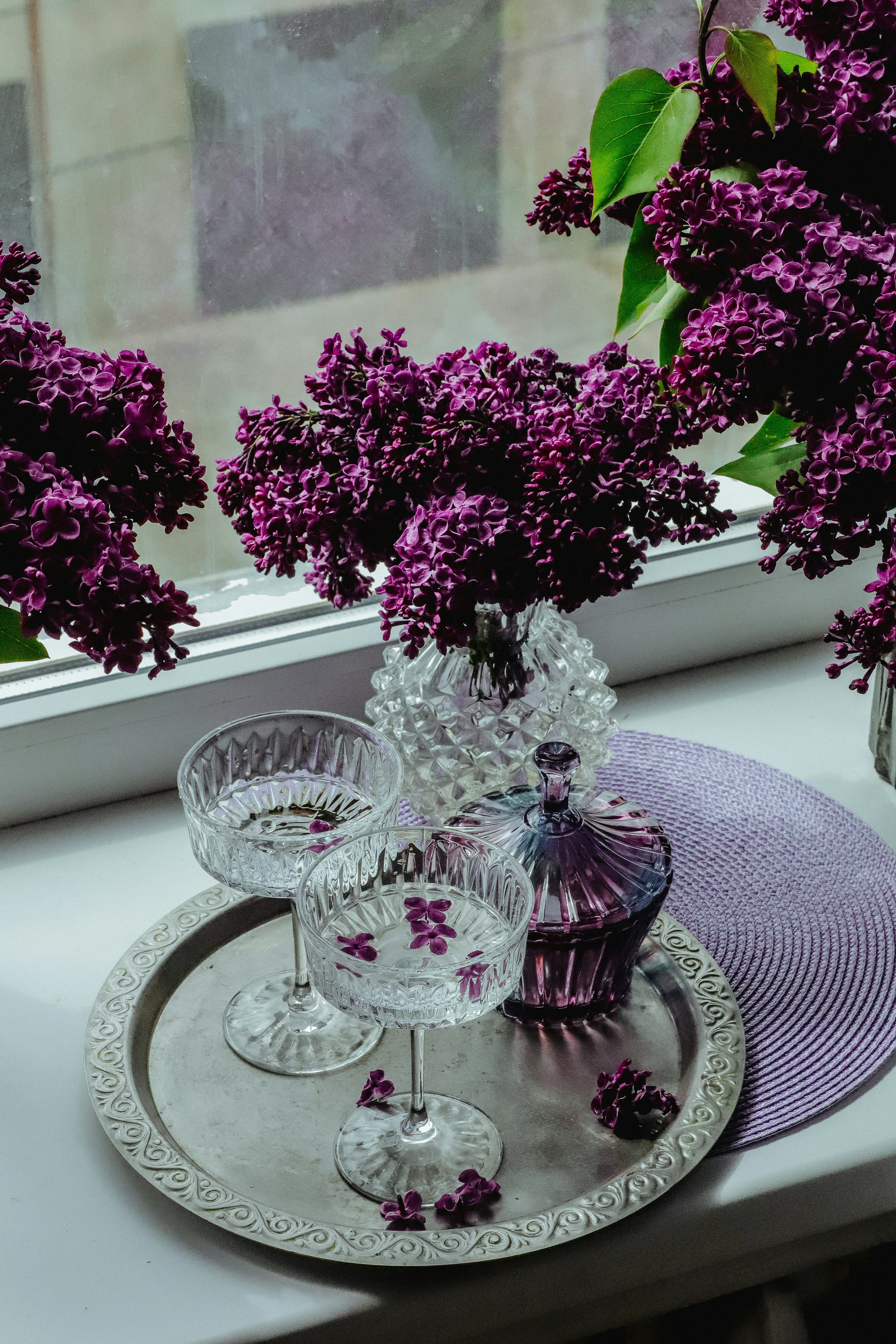 purple flowers in a glass vase on a tray