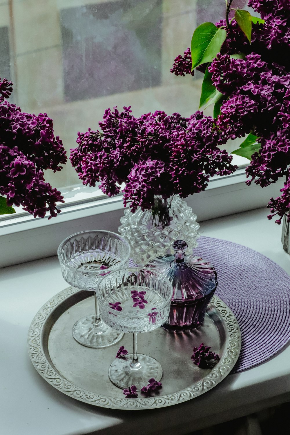 purple flowers in a glass vase on a tray