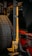 A mechanical jack with a yellow handle is mounted next to a spare tire on the rear of a red vehicle. The jack has multiple adjustment holes along its vertical frame. A bottle of wheel cleaner is visible next to it.