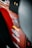 A close-up view of a red vehicle panel adorned with multiple brand stickers, including AEM and Trail Rated 4x4. The focus is on the stickers with some parts of the vehicle's interior visible.