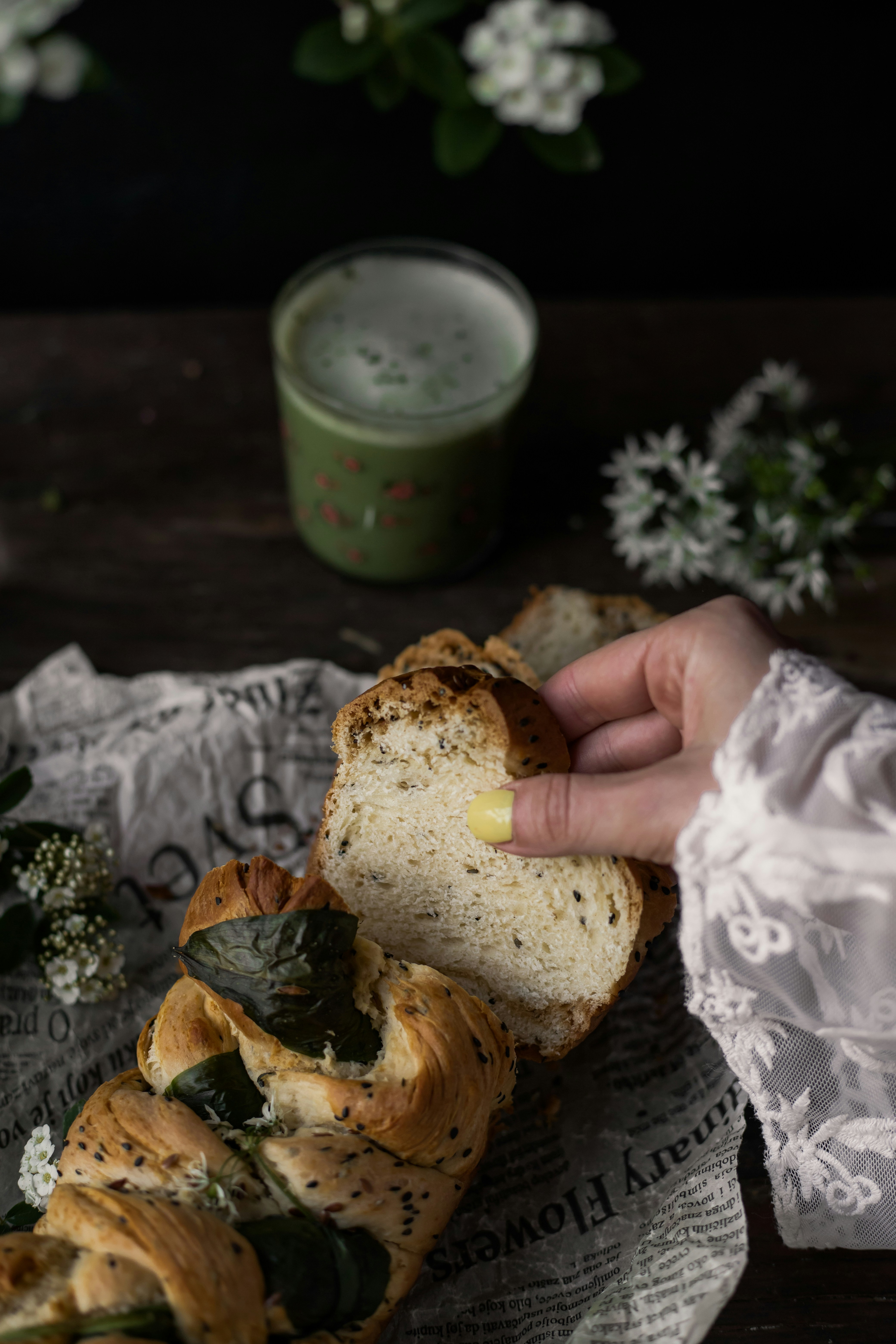 A hand picking up a piece of homemade ramsons (wild garlic) bread | Matcha latte in the background || 📸 Photo by: Jovan Vasiljević