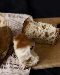 Photographer capturing a styled shot of artisanal bread and cheese on parchment paper with deep crimson accents