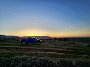 Red pickup truck with trailer parked on a country road at sunset.
