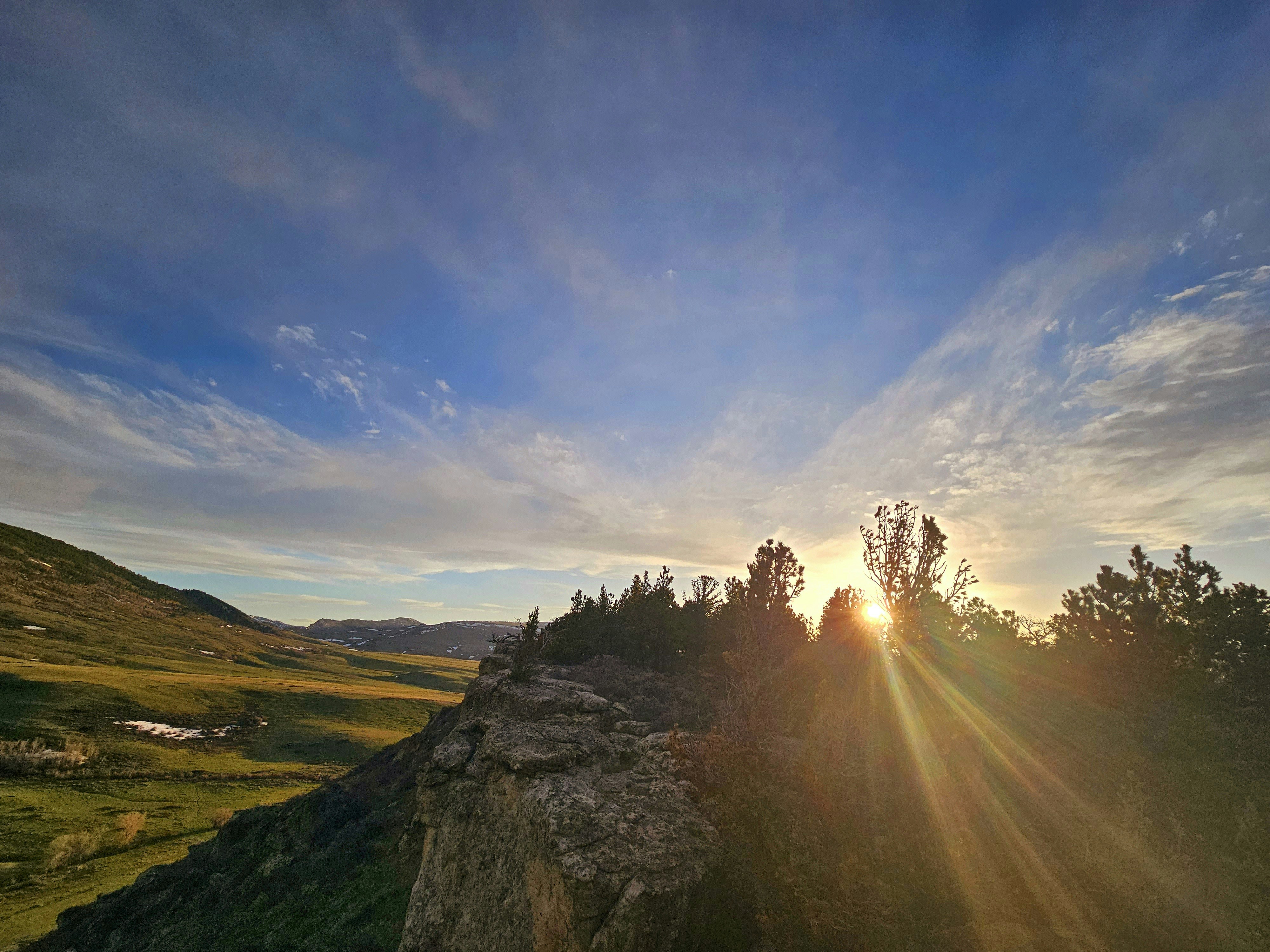Mountain sunrise with rays of golden light breaking through clouds over a peaceful valley