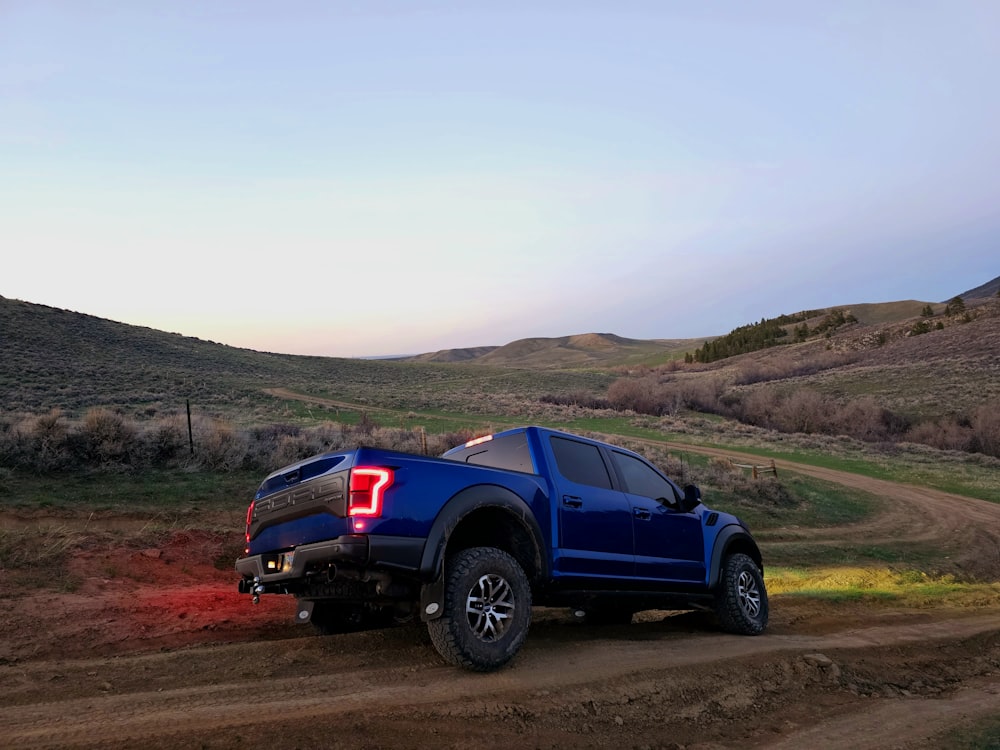 a blue truck driving down a dirt road