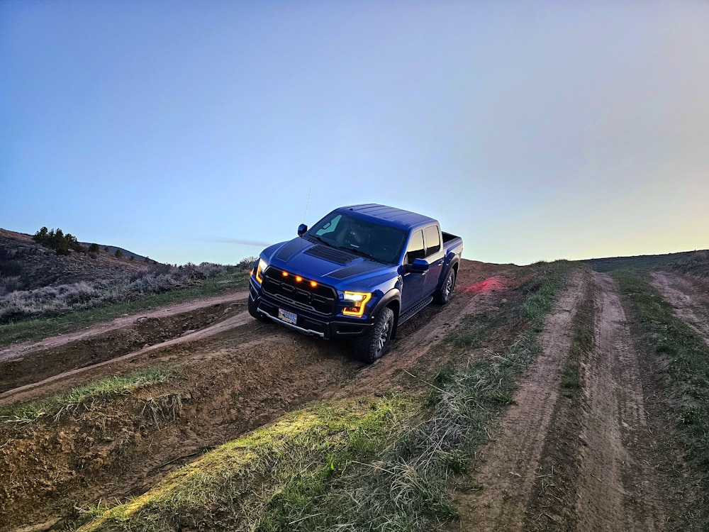 a blue truck driving down a dirt road