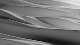 Smooth, flowing abstract patterns create a serene and minimalist aesthetic. The soft curves and gradients suggest a sense of movement and calm.
