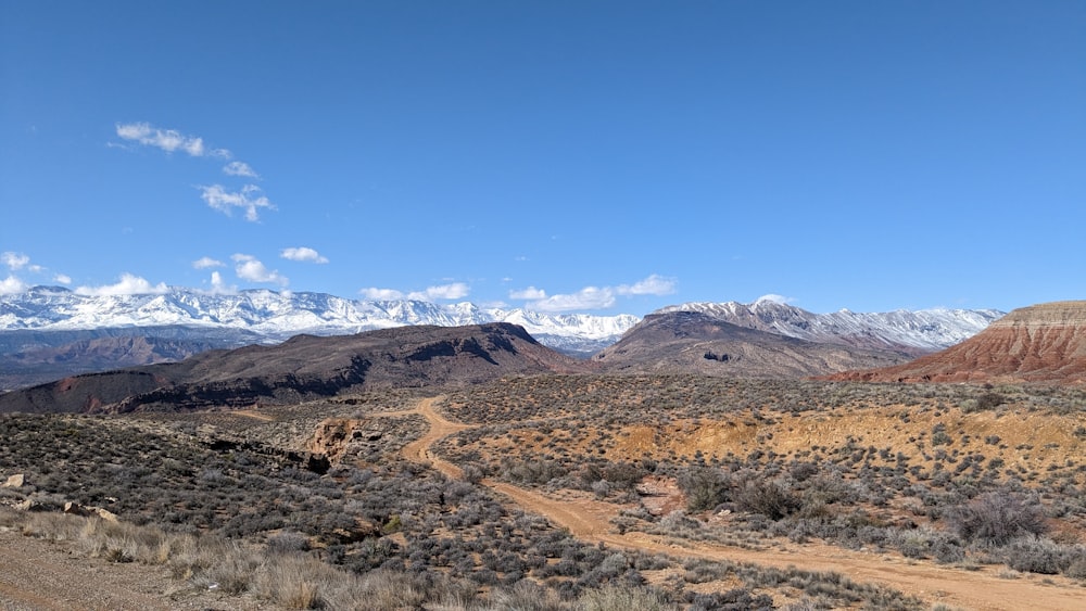 a dirt road in the desert with mountains in the background