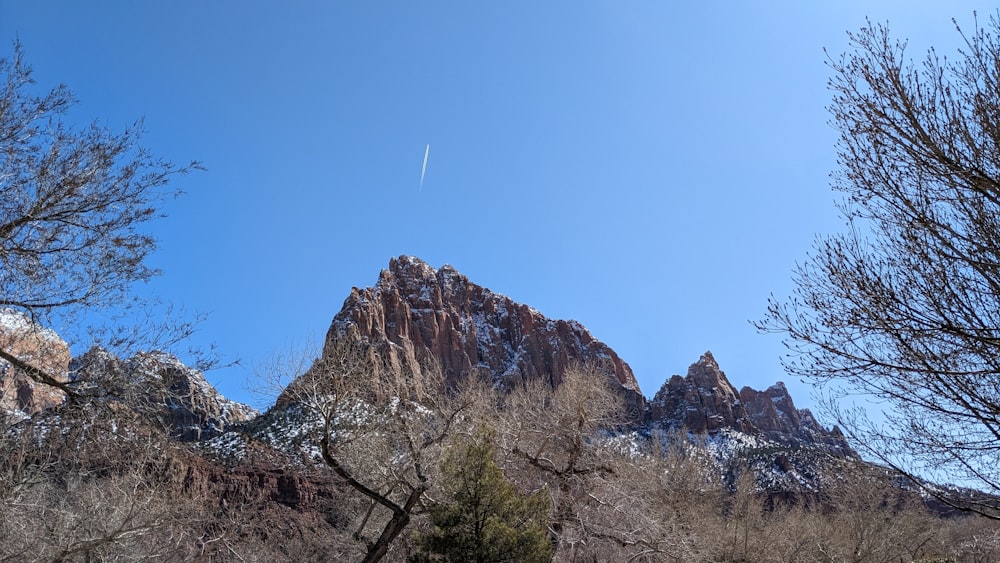 a view of a mountain with a plane flying in the sky