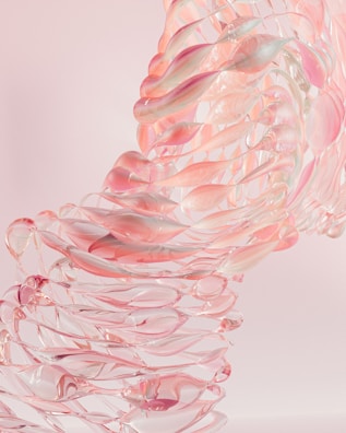 An abstract arrangement of translucent pink and clear shapes, reminiscent of glass or crystal, forming a twisting, flowing structure against a light pastel background.