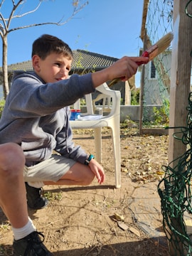 A person painting a wooden project in their backyard.