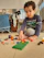A joyful child building with wooden blocks from Podaro, bathed in soft natural light.