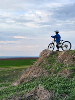 Cyclist pausing on a hilltop with panoramic views of rolling gravel roads.