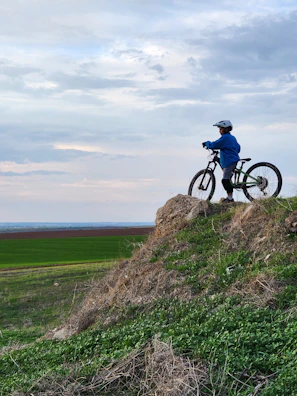 Cyclist pausing on a hilltop with panoramic views of rolling gravel roads.