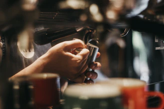 Hands adjusting espresso machine settings with coffee tools arranged neatly nearby.
