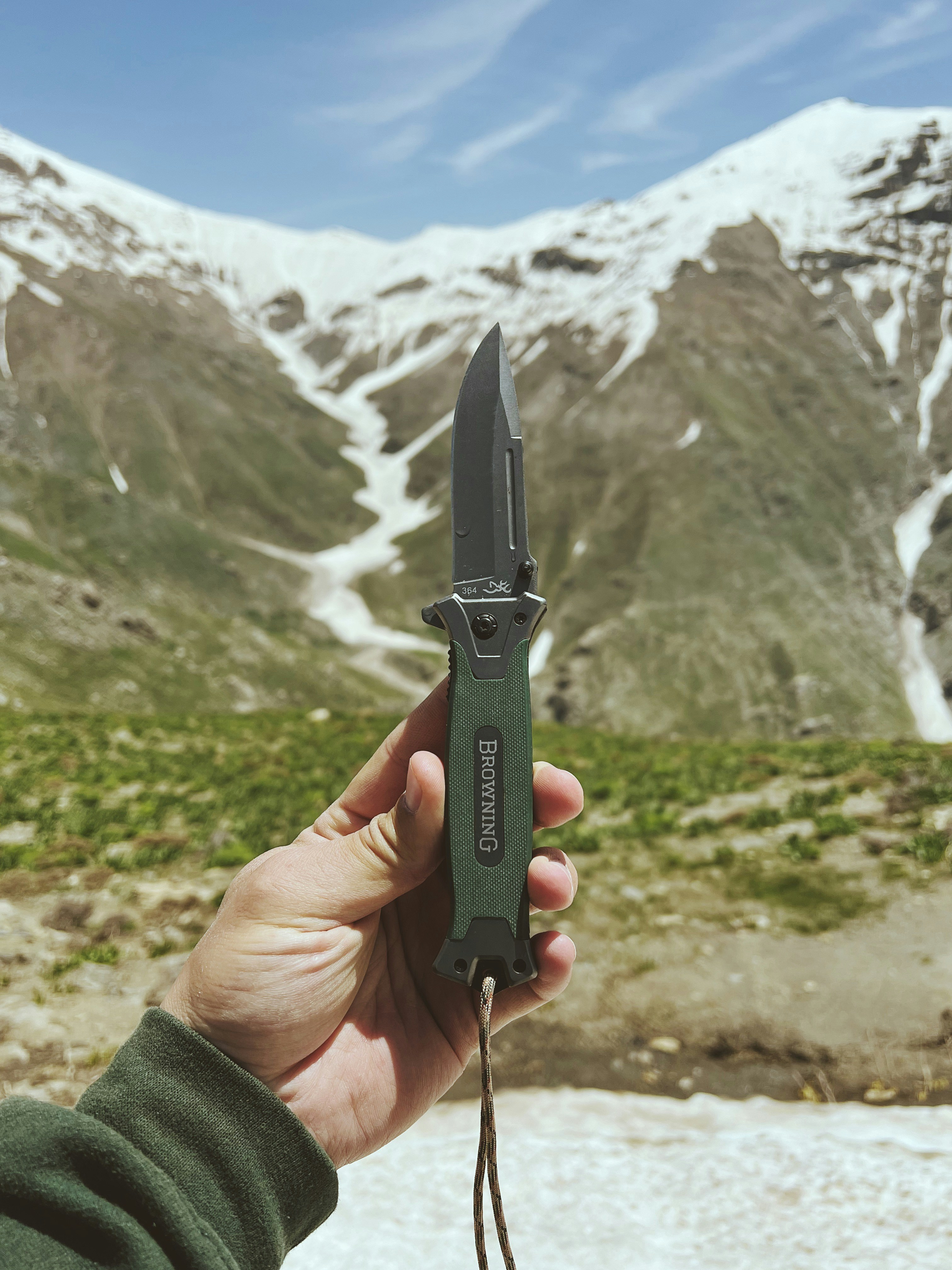 Una persona sosteniendo un cuchillo frente a una montaña