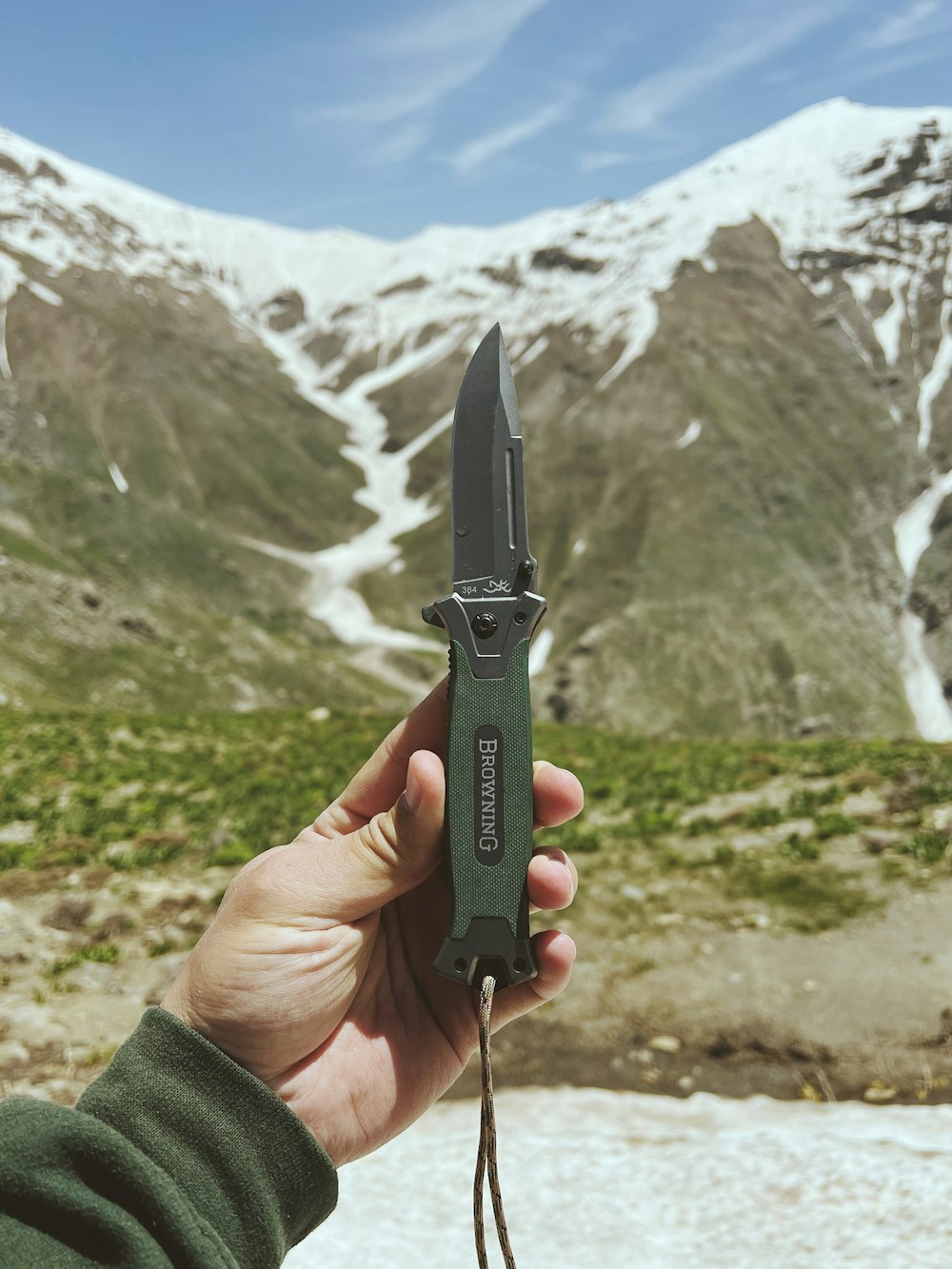 a person holding a knife in front of a mountain
