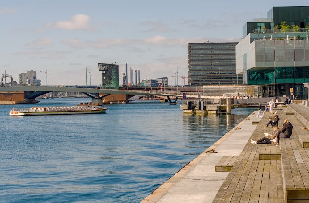 a man sitting on a dock next to a body of water