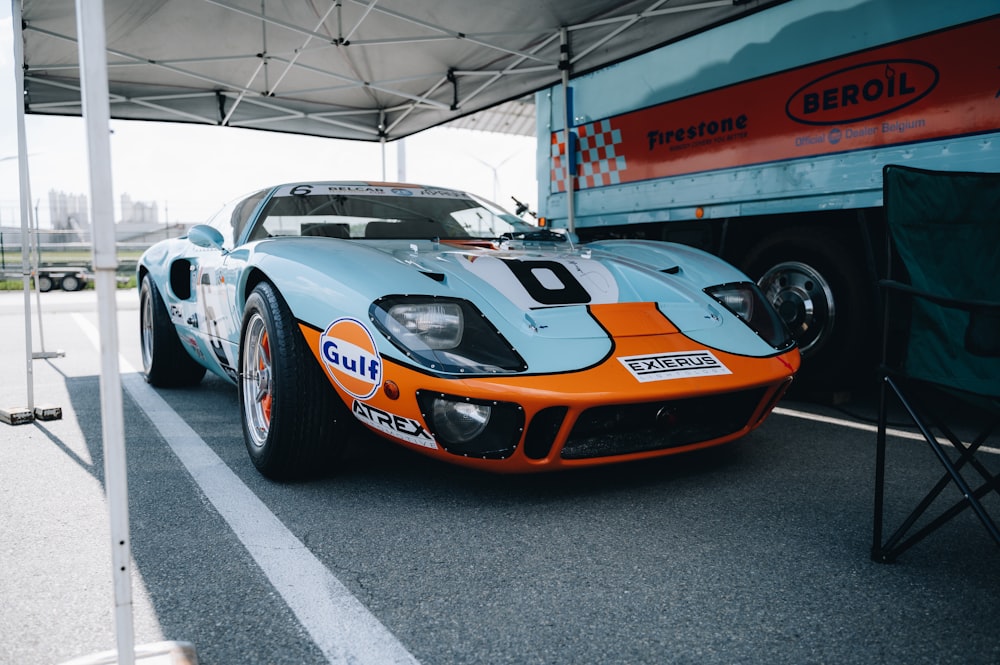 an orange and blue race car parked in a parking lot