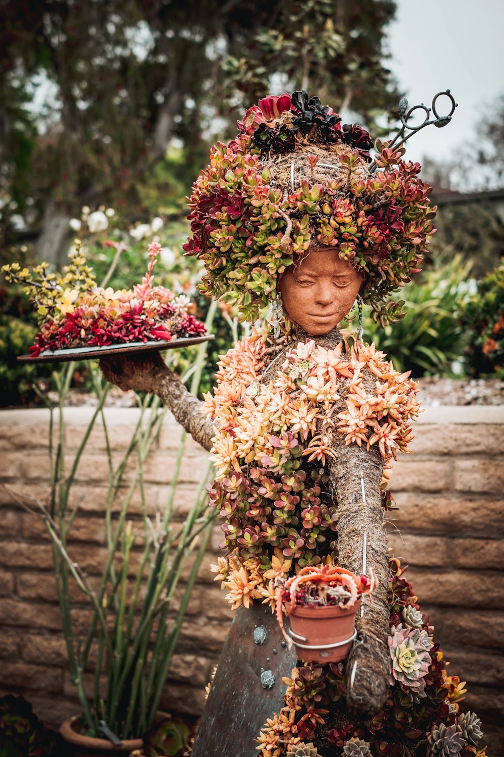 a statue of a woman holding a tray of flowers