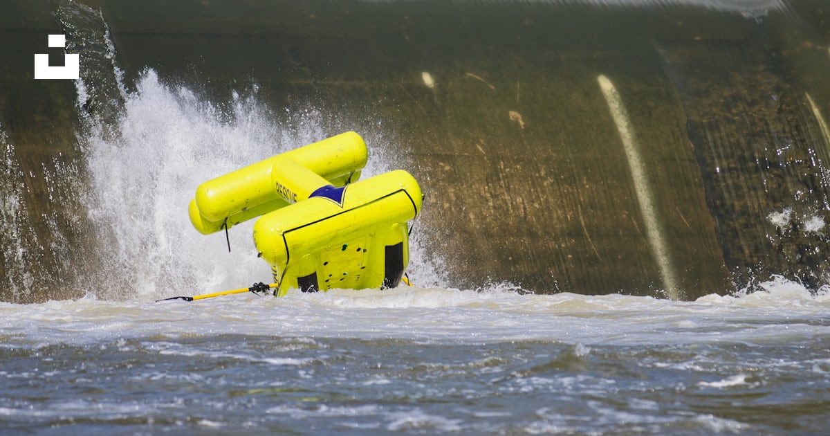 A yellow raft in the water near a waterfall photo – Free Splash Image ...