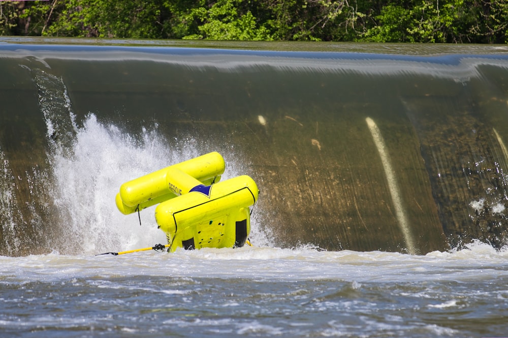 a yellow raft in the water near a waterfall