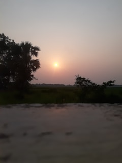 A serene landscape photograph taken during a sunset, highlighting warm tones.
