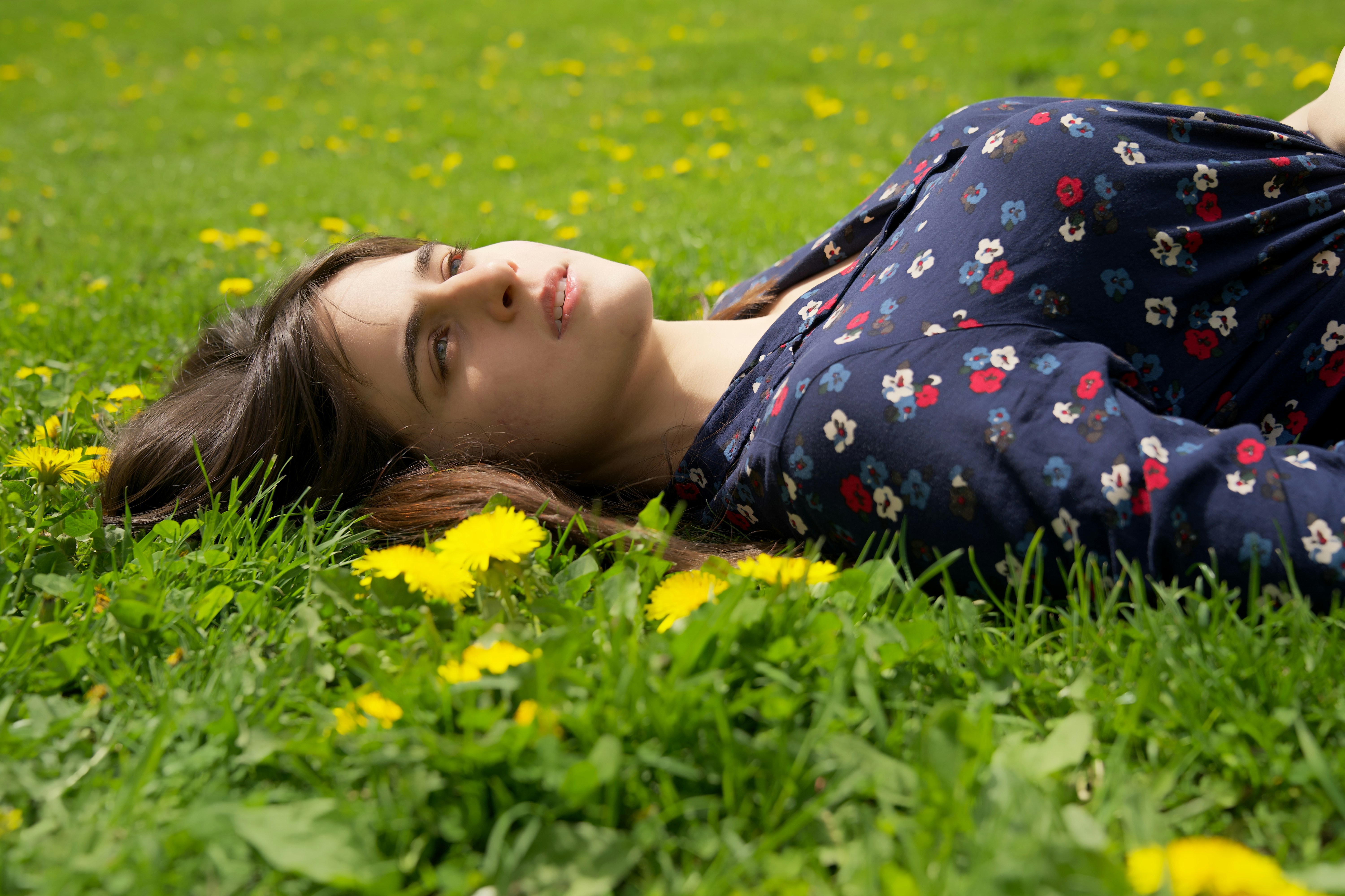 a woman laying in the grass with her eyes closed